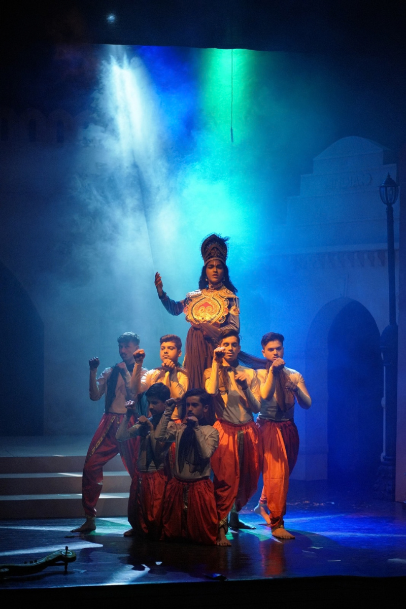 Costumed ensemble in a dramatic tableau on stage